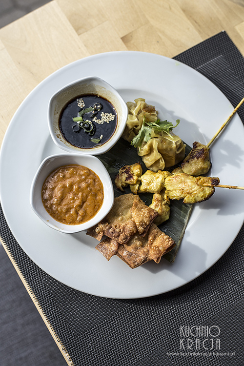 Talerz z przekąskami na ciepło - chrupiące pierożki wonton, grillowane mini szaszłyki z piersi kurczaka, pierożki Dim Sum gotowane na parze z nadzieniem z kurczaka i krewetek. Podawany z dwoma sosami - orzechowym z curry i sojowo-imbirowym, Restauracja Basil & Lime
